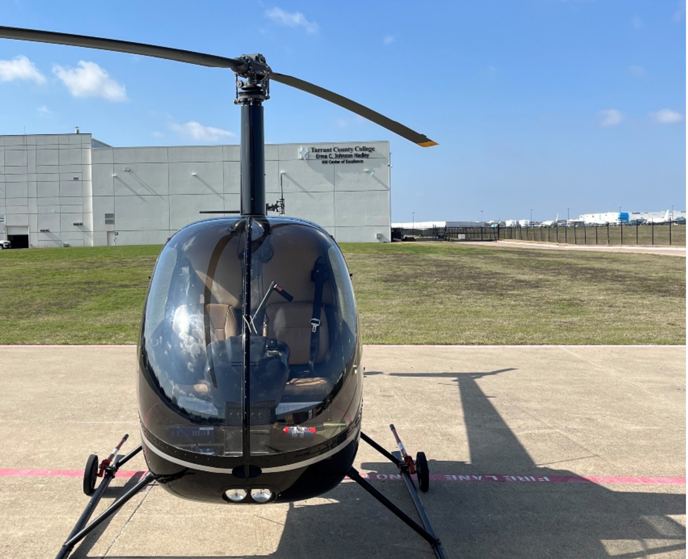 Black R22 Helicopter in front of Tarrant County College Aviation Training Center Building